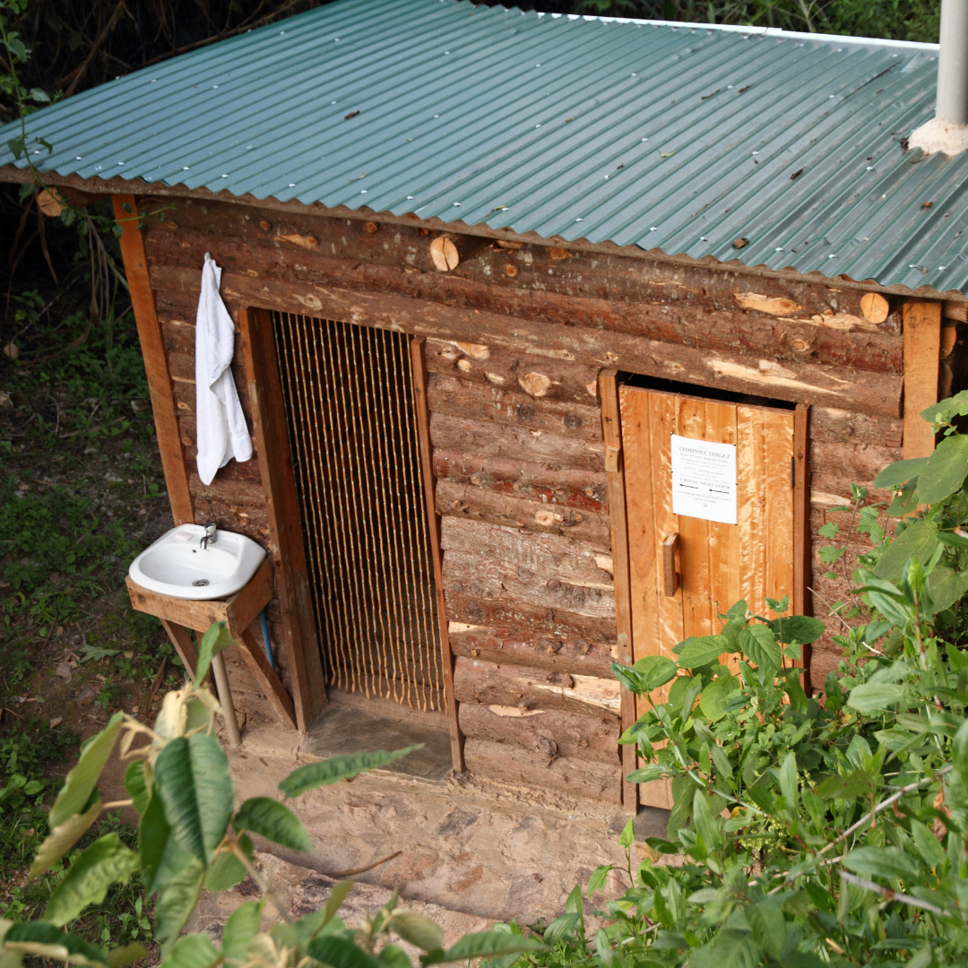 wooden outhouse bathroom building with sink and shower curtain